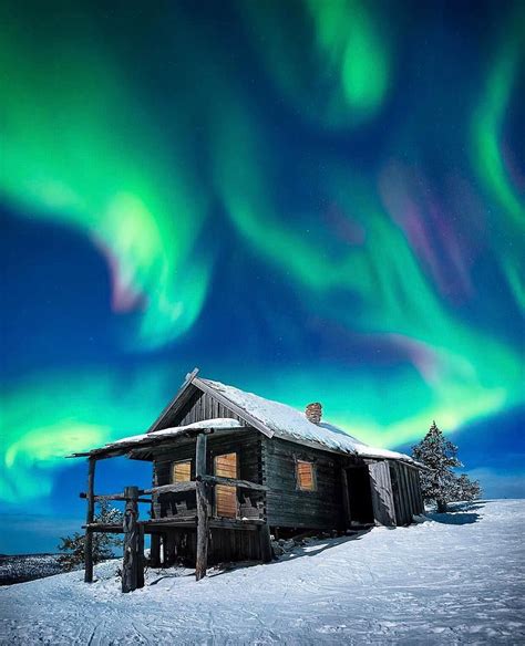 An Old Cabin In The Snow With Aurora Lights