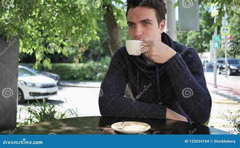 Young Man Drinking Coffee While Sitting In Cafe Terrace Stock Photo