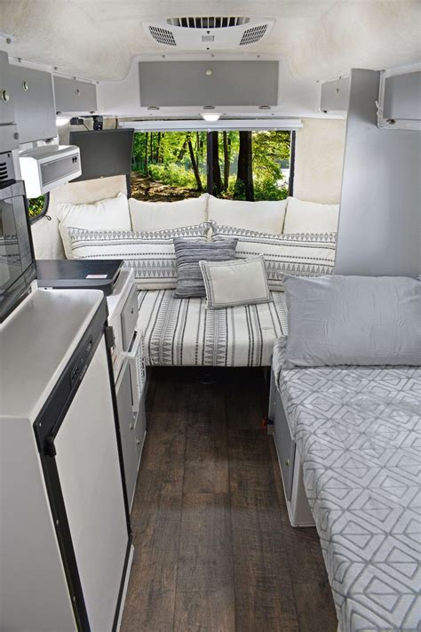 the inside of a camper with a bed, sink and refrigerator