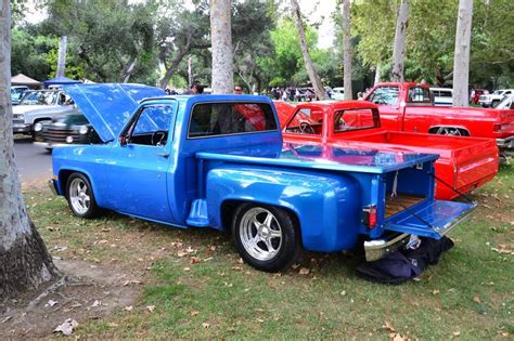 An Old Blue Pickup Truck Parked Next To Other Red And White Trucks At A