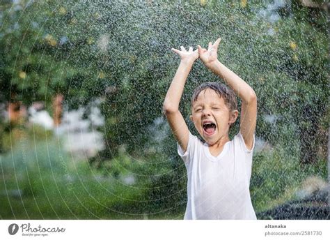 Happy Little Boy Pouring Water From A Hose A Royalty Free Stock