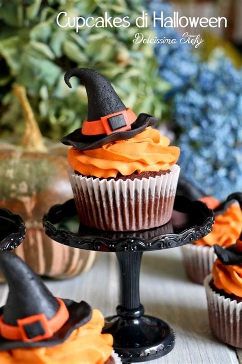 Cupcakes Decorated With Orange Frosting And Black Witches Hats Are On A