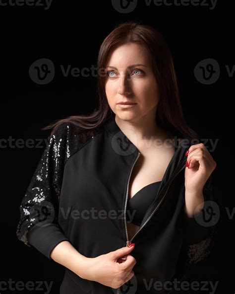 Shy Brunette Woman Unzipping Black Jacket And Showing Bra Looking Up