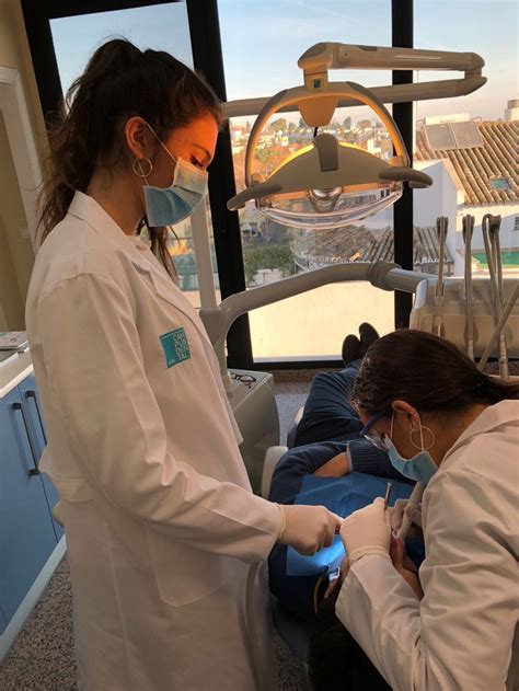 Two Women In White Lab Coats And Masks Working On A Patient S Teeth At