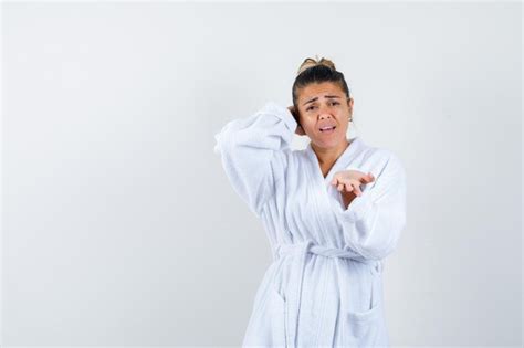 Mulher jovem roupão de banho branco esticando a mão e recebendo