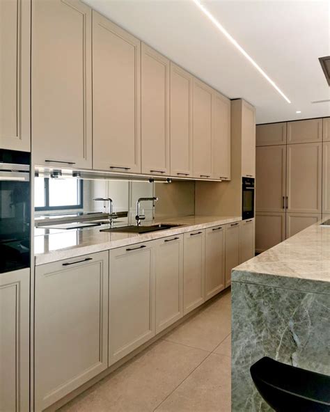 A Kitchen With White Cabinets And Marble Counter Tops Along With An