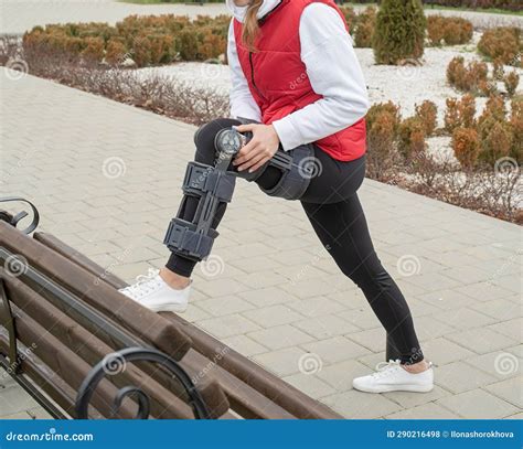 Woman Wearing Knee Brace Or Orthosis After Leg Surgery Walking In The