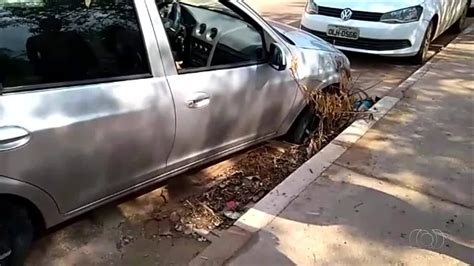 Carro fica preso em bueiro aberto e é removido ajuda de outro