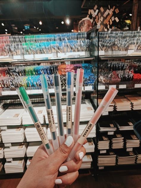 a person holding five different colored pens in front of a store ...