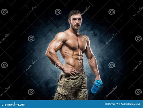 Hombre Joven Muscular En Estudio En Fondo Oscuro Imagen De Archivo