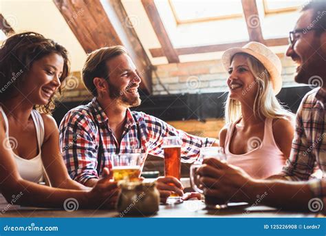 Pares Novos Que Bebem A Cerveja E Que Riem Junto Na Barra Foto De Stock