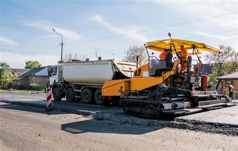 Premium Photo Worker Operating Asphalt Paver Machine During Road