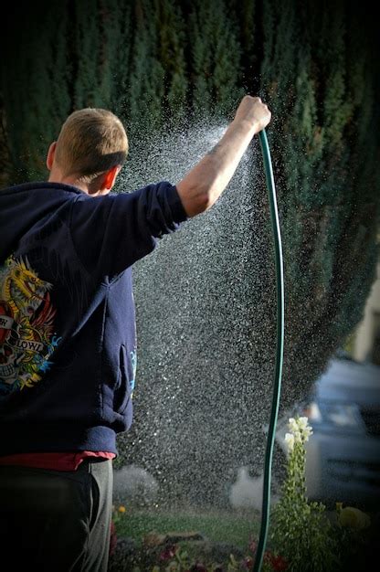 Hombre Sosteniendo Una Tuber A Rociando Agua En El Parque Foto Premium