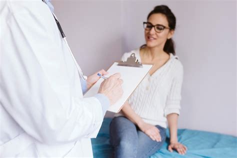 Premium Photo Midsection Of Doctor Writing On Clipboard By Patient