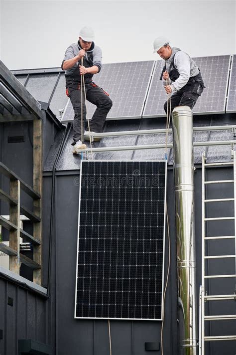 Workers Lifting Up Photovoltaic Solar Module While Installing Solar