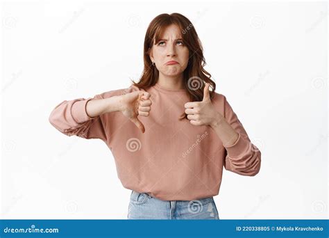 Image Of Hesitant Young Woman Thinking While Showing Thumbs Up Down