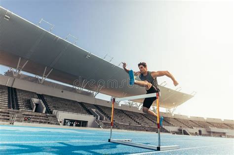 Athlete Jumping Over An Hurdle On Running Track Stock Photo Image Of