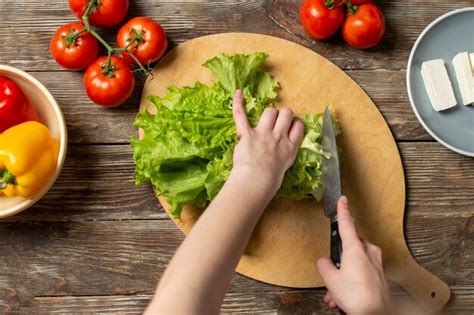 Premium Photo Hands Of The Girl Cutting Lettuce On A Table