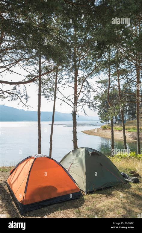 Tents in the forest in front of mountain lake Stock Photo - Alamy