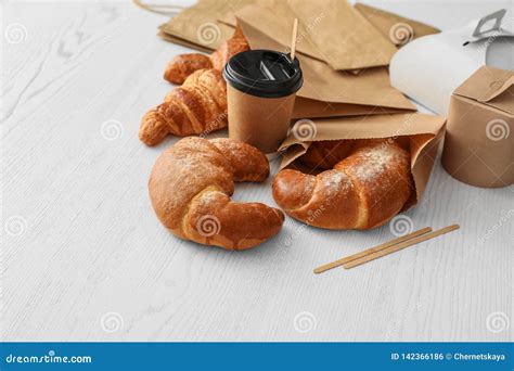 Paper Bags With Pastry And Takeaway Food On Light Table Stock Photo