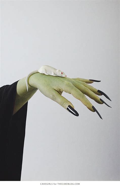 A Woman With Green Hands And Black Nails Is Holding Something In Her