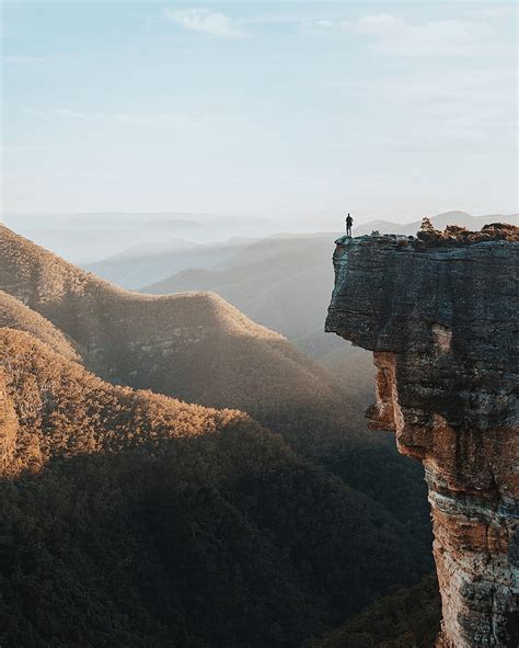 Man Standing On Rock Cliff Overlooking Mountains Hd Phone Wallpaper