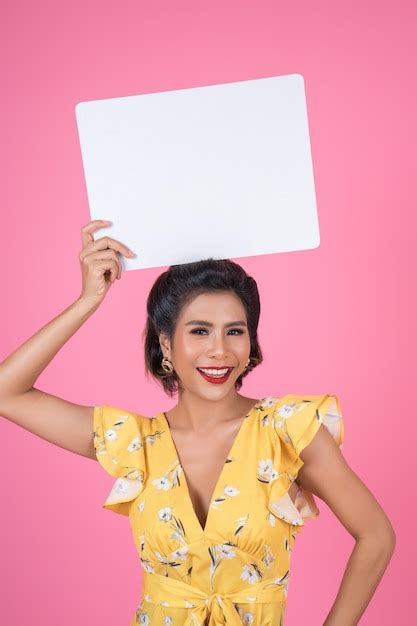 Retrato De Uma Jovem Sorridente Segurando Um Cartaz Em Branco Contra Um