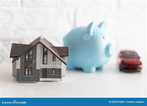 Real Estate House Model With Key And Piggy Bank On Table Stock Photo