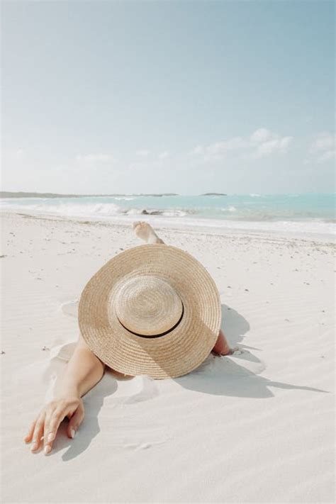 Unrecognizable woman in hat lying on beach · Free Stock Photo