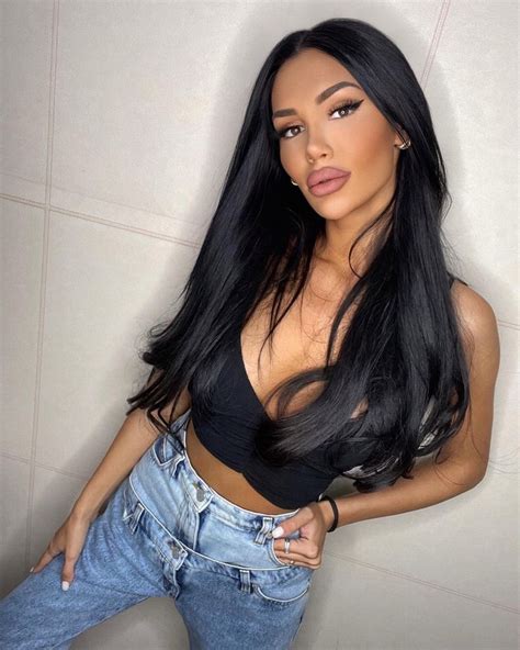 A Woman With Long Black Hair Posing For The Camera Wearing Jeans And A Crop Top