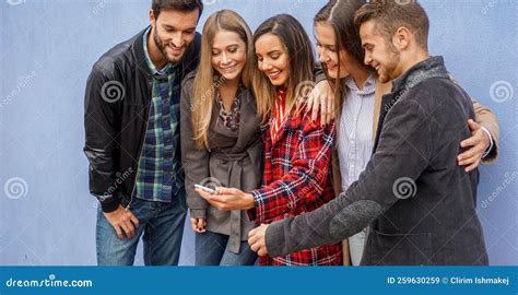 Group Of People Standing By The Wall And Sharing Online Stuff Friends