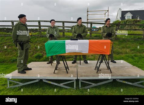 Men dressed in IRA paramilitary uniforms with a coffin draped in an ...