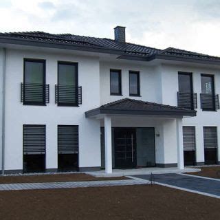 A Large White Building With Black Shutters On The Windows