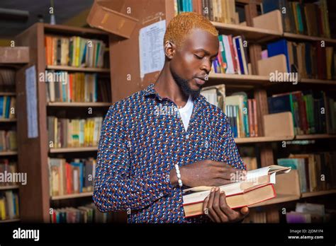 Young man reading book in library Stock Photo - Alamy