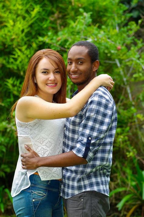 Beautiful Young Interracial Couple In Sitting Garden Environment Embracing And Smiling Happily