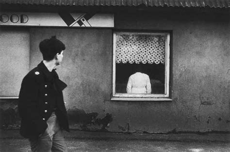 A Black And White Photo Of A Man Walking In Front Of A Building With A