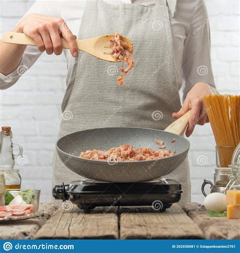 Professional Chef In White Uniform Stir Frying Bacon In Pan For Cooking