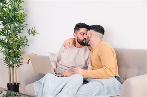 Romantique Jeune Couple Gay Assis Sur Un Canapé S embrassant Photo Gratuite