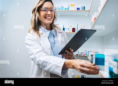 Happy Pharmacist Getting Medication From A Shelf In A Chemist Female