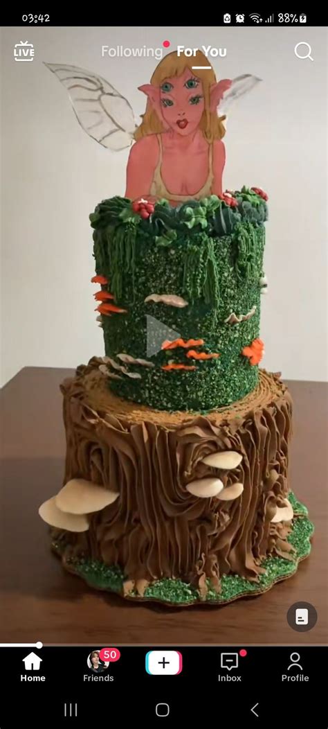 A Green Cake With A Fairy Sitting On Top Of It S Tree Stumps