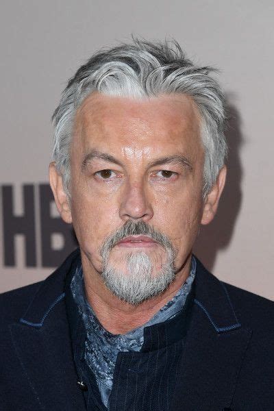 An Older Man With Grey Hair And Beard Wearing A Suit