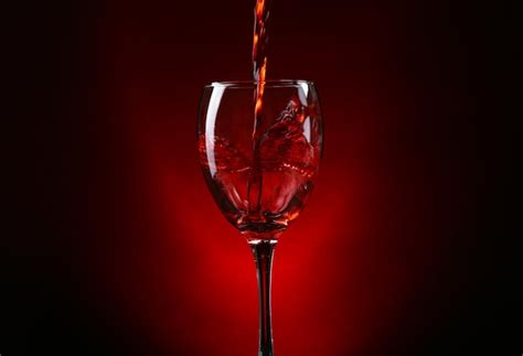 Premium Photo Wine Pouring In Glass On Dark Red Background