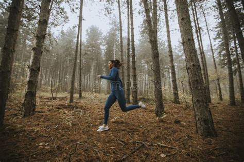 Young Woman Running Toward Camera On The Forest Trail At Autumn Stock