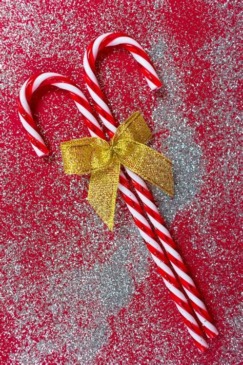 Two Christmas Candies With A Golden Bow On A Shiny Red Background