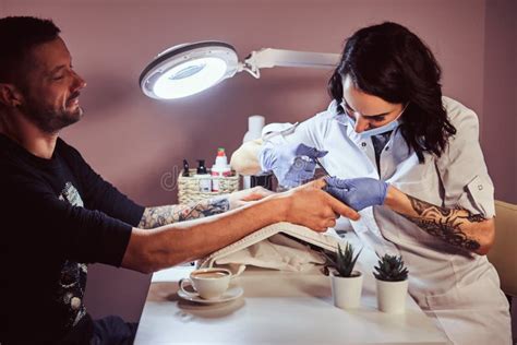 Un Hombre Con Un Tatuaje En Su Mano Que Recibe Una Manicura De Un