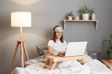 Portrait Of Smiling Attractive Woman Wearing Sleeping Mask Working On