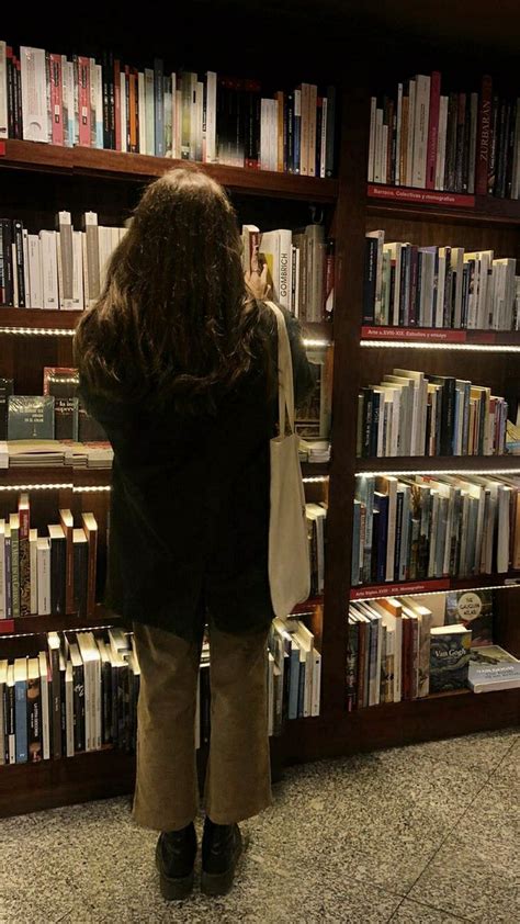 A Woman Standing In Front Of A Book Shelf Filled With Books