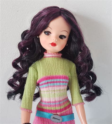 A Close Up Of A Doll Wearing A Green Sweater And Pink Skirt With Black