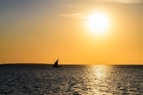 Barco a vela tradicional dhow no oceano índico ao pôr do sol Foto Premium