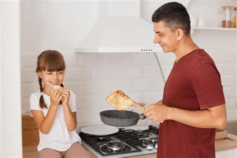 Imagem De Homem Caucasiano Cozinhando Panquecas Filha Na Cozinha